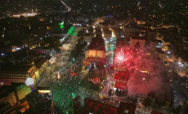 Fireworks and light beams illuminate the sky as people fill Clock Square in central Homs, western Syria, Monday, Dec. 8, 2025, to mark the first anniversary of the ousting of the Bashar Assad regime. (AP Photo/Omar Albam)