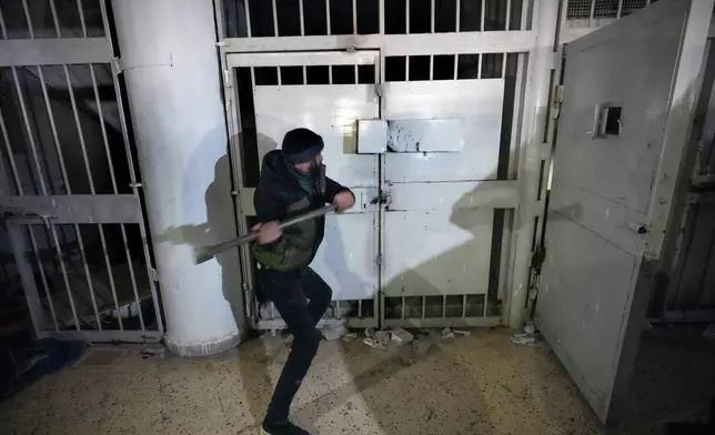 FILE - A man breaks the lock of a cell in the infamous Saydnaya military prison, just north of Damascus, Syria, Monday, Dec. 9, 2024. (AP Photo/Hussein Malla, File)