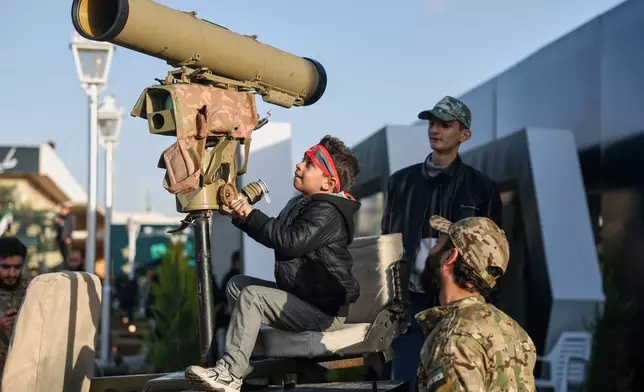 A boy checks out military equipment as visitors tour the "Syrian Revolution Military Exhibition," which opened last week ahead of the first anniversary of the ousting of the Bashar Assad regime in Damascus, Syria, Sunday, Dec. 7, 2025. (AP Photo/Ghaith Alsayed)