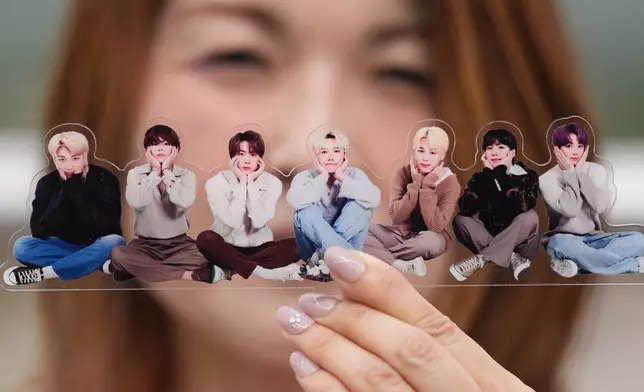 A fan poses with a group photo of BTS, also known as the Bangtan Boys, during a celebration marking the South Korean's K-pop band's 12th debut anniversary in Goyang, South Korea, June 13, 2025. (AP Photo/Lee Jin-man, File)