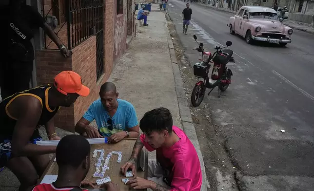 People play dominoes outdoors during a power outage in Havana, Cuba, Wednesday, Dec. 3, 2025. (AP Photo/Ramon Espinosa)