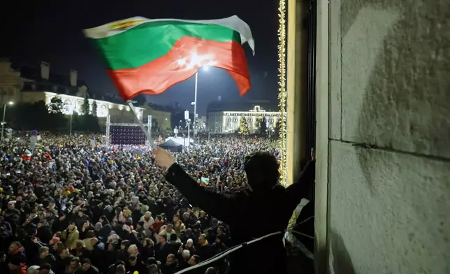 A student waves a Bulgarian flag as a swelling crowd of tens of thousands of Bulgarians filled Sofia's central square, demanding the government's resignation amid rising anger over corruption and contested economic policies, Sofia, Bulgaria, Wednesday, Dec. 10, 2025. (AP Photo/Valentina Petrova)