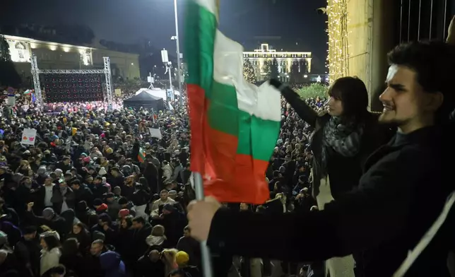Students wave Bulgarian flag as as a swelling crowd of tens of thousands of Bulgarians filled Sofia's central square, demanding the government's resignation amid rising anger over corruption and contested economic policies, Sofia, Bulgaria, Wednesday, Dec. 10, 2025. (AP Photo/Valentina Petrova)