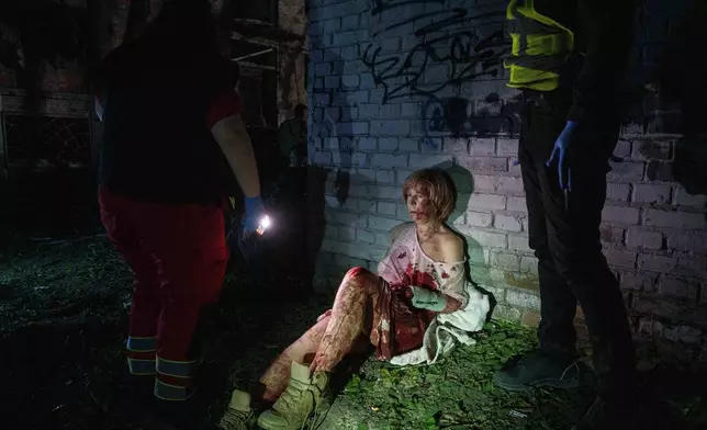 An injured woman sits near her house, which was damaged by a Russian airstrike, in a residential neighborhood in Kyiv, Ukraine, on April 24, 2025. (AP Photo/Evgeniy Maloletka, File)