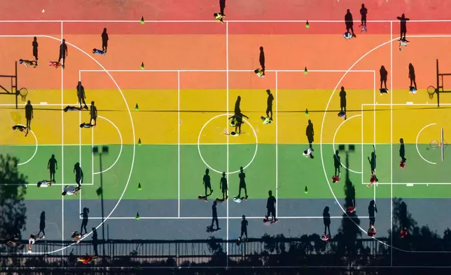 Children cast shadows on a basketball court during a sports workshop at a park in Santiago, Chile, on Feb. 18, 2025. (AP Photo/Matias Basualdo, File)