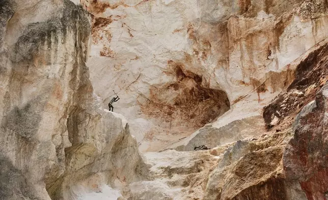 A worker pounds into rock to make gravel and sand in Kenscoff, a neighborhood of Port-au-Prince, Haiti, on July 24, 2025. (AP Photo/Odelyn Joseph, File)