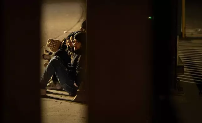 A group of migrants wait to be processed between two border walls separating Mexico and the United States after crossing illegally before dawn, Jan. 21, 2025, in San Diego. (AP Photo/Gregory Bull, File)