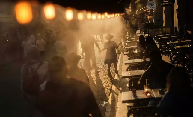 A coffee bar in Istanbul sprays mist to cool people passing by on July 24, 2025. (AP Photo/Francisco Seco, File)