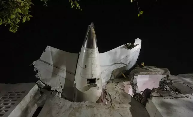 The tail of an airplane sticks out of a building where it crashed in Ahmedabad, India, on June 12, 2025. (AP Photo/Ajit Solanki, File)