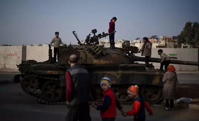 FILE - Children on the top of an ousted Syrian government forces tank that was left on a street in an Alawite neighbourhood, in Homs, Syria, Dec. 26, 2024. (AP Photo/Leo Correa, File)