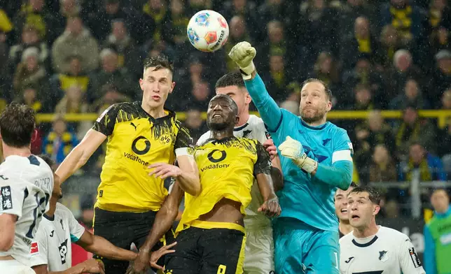 Borussia's Nico Schlotterbeck, top left, abd Serhou Guirassy, centre, challenge for the ball with Hoffenheim's goalkeeper Oliver Baumann during Germany Bundesliga soccer match between Borussia Dortmund and TSG 1899 Hoffenheim, in Dortmund, Germany, Sunday, Dec. 7, 2025. (Bernd Thissen/dpa via AP)