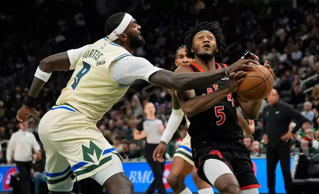 Milwaukee Bucks' Bobby Portis (9) hits the ball away from Toronto Raptors' Immanuel Quickley during the first half of an NBA basketball game, Thursday, Dec. 18, 2025, in Milwaukee. (AP Photo/Aaron Gash)