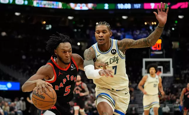 Toronto Raptors' Immanuel Quickley (5) drives to the basket against Milwaukee Bucks' Kevin Porter Jr. (7) during the first half of an NBA basketball game Thursday, Dec. 18, 2025, in Milwaukee. (AP Photo/Aaron Gash)