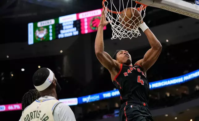 Toronto Raptors' Scottie Barnes (4) dunks past Milwaukee Bucks' Bobby Portis during the first half of an NBA basketball game, Thursday, Dec. 18, 2025, in Milwaukee. (AP Photo/Aaron Gash)