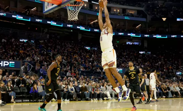 Phoenix Suns forward Oso Ighodaro (11) goes up to dunk against Golden State Warriors forward Jimmy Butler III (10) during the first half of an NBA basketball game in San Francisco, Saturday, Dec. 20, 2025. (AP Photo/Jed Jacobsohn)