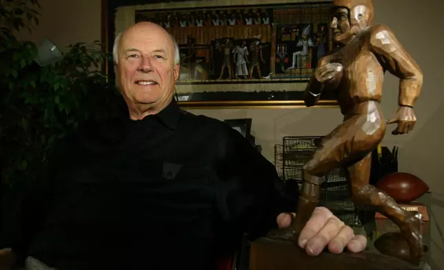 FILE - Chuck Neinas sits in his home office with an old football trophy, Feb. 27, 2003, in Boulder, Colo. (AP Photo/Jack Dempsey, File)