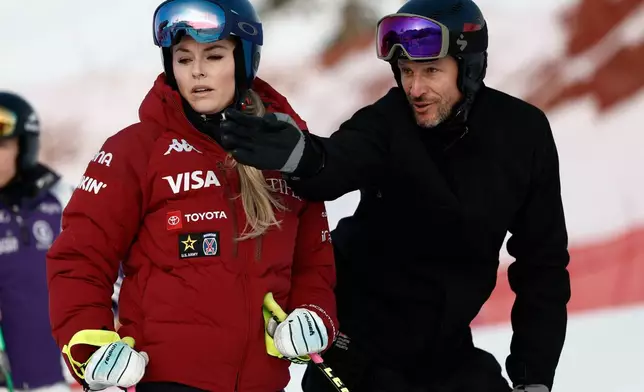 United States' Lindsey Vonn listens to Aksel Lund Svindal ahead of an alpine ski, women's World Cup downhill in St. Moritz, Switzerland, Friday Dec. 12, 2025. (AP Photo/Gabriele Facciotti)