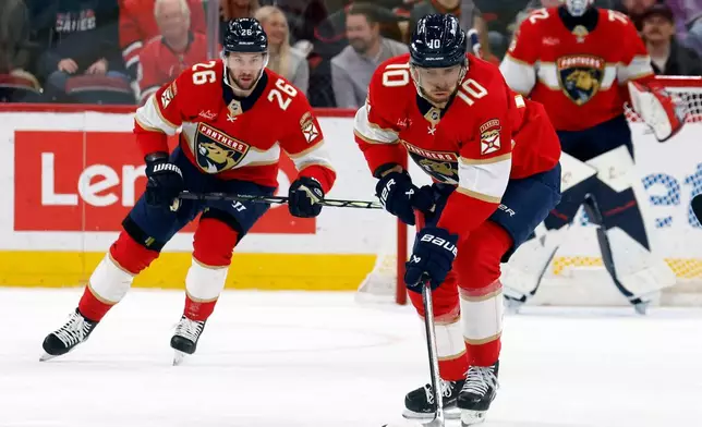Florida Panthers' A.J. Greer (10) settles the puck with Florida Panthers' Uvis Balinskis (26) nearby during the first period of an NHL hockey game against the Carolina Hurricanes in Raleigh, N.C., Tuesday, Dec. 23, 2025. (AP Photo/Karl DeBlaker)