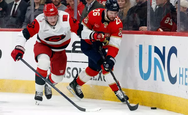Florida Panthers' Uvis Balinskis (26) clears the puck in front of Carolina Hurricanes' Eric Robinson (50) during the second period of an NHL hockey game in Raleigh, N.C., Tuesday, Dec. 23, 2025. (AP Photo/Karl DeBlaker)