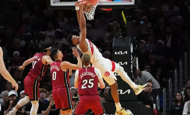 Toronto Raptors forward Scottie Barnes, right, dunks during the first half of an NBA basketball game against the Miami Heat, Tuesday, Dec. 23, 2025, in Miami. (AP Photo/Lynne Sladky)