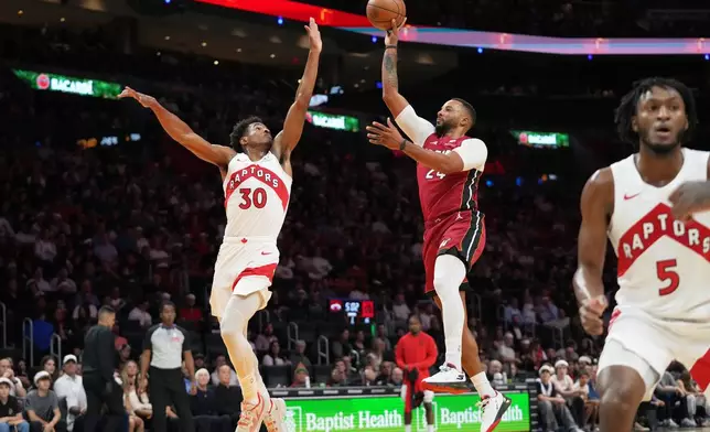 Miami Heat guard Norman Powell, right, goes to the basket as Toronto Raptors guard Ochai Agbaji (30) defends during the first half of an NBA basketball game, Tuesday, Dec. 23, 2025, in Miami. (AP Photo/Lynne Sladky)