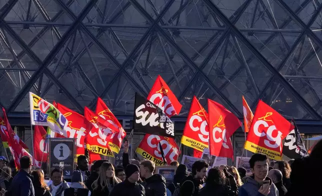 Workers display union flags and banners outside the Louvre museum after they voted to strike for the day over working conditions and other complaints, Monday, Dec. 15, 2025 in Paris. (AP Photo/Michel Euler)