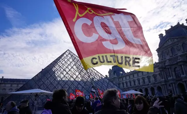 Workers display an union flag outside the Louvre museum after they voted to strike for the day over working conditions and other complaints, Monday, Dec. 15, 2025 in Paris. (AP Photo/Michel Euler)