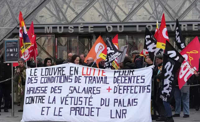 Unionists display a banner and union flags outside the Louvre museum after employees have voted to extend a strike that has disrupted operations at the world's most visited museum, Wednesday, Dec. 17, 2025 in Paris. (AP Photo/Christophe Ena)