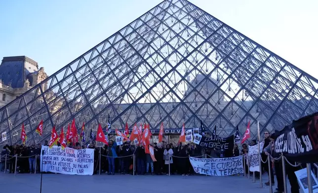 Workers display banners outside the Louvre museum after they voted to strike for the day over working conditions and other complaints, Monday, Dec. 15, 2025 in Paris. (AP Photo/Michel Euler)