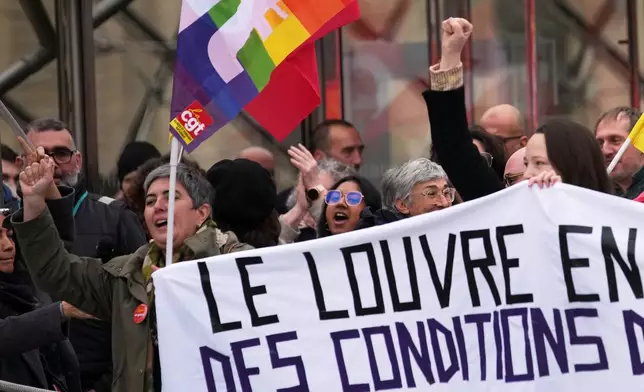 Unionists display a banner and union flags outside the Louvre museum after employees have voted to extend a strike that has disrupted operations at the world's most visited museum, Wednesday, Dec. 17, 2025 in Paris. (AP Photo/Christophe Ena)