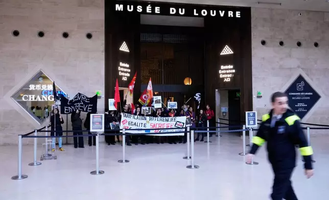 Workers display banners at an entrance of the Louvre museum after they voted to strike for the day over working conditions and other complaints, Monday, Dec. 15, 2025 in Paris. (AP Photo/Michel Euler)