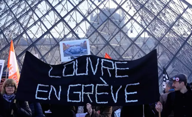 Workers display a banner reading "Louvre on strike" outside the Louvre museum after they voted to strike for the day over working conditions and other complaints, Monday, Dec. 15, 2025 in Paris. (AP Photo/Michel Euler)