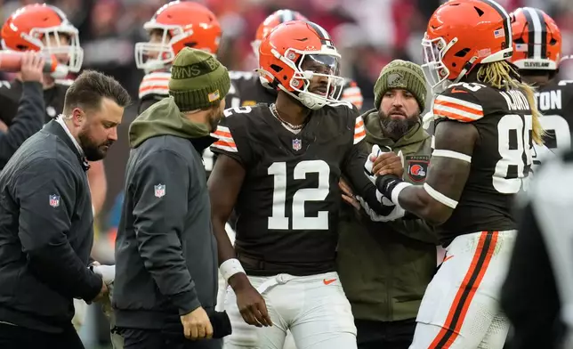 Cleveland Browns quarterback Shedeur Sanders (12) is helped off the field by tight end David Njoku (85) and trainers during the second half of an NFL football game against the San Francisco 49ers, Sunday, Nov. 30, 2025, in Cleveland. (AP Photo/Sue Ogrocki)