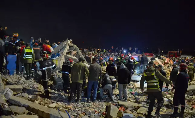 Rescue workers and reisdents search for survivors amid the wreckage of two collapsed buildings in Fez, Morocco, Tuesday, Dec. 9, 2025. (AP Photo/Ahmed Alaoui Mrani)