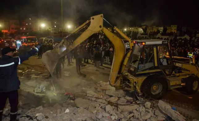 Rescue workers and residents search for survivors amid the wreckage of two collapsed buildings in Fez, Morocco, Tuesday, Dec. 9, 2025. (AP Photo/Ahmed Alaoui Mrani)