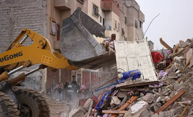 Rescue workers search for survivors, amid the wreckage of two collapsed buildings, in Fez, Morocco, Wednesday, Dec. 10, 2025. (AP Photo/Hanane Boukili)