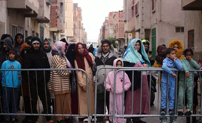 Residents watch as rescue workers search for survivors, amid the wreckage of two collapsed buildings, in Fez, Morocco, Wednesday, Dec. 10, 2025. (AP Photo/Hanane Boukili)