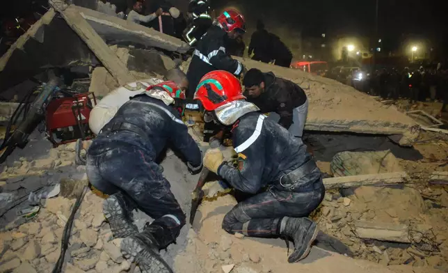 Rescue workers and residents search for survivors amid the wreckage of two collapsed buildings in Fez, Morocco, Tuesday, Dec. 9, 2025. (AP Photo/Ahmed Alaoui Mrani)