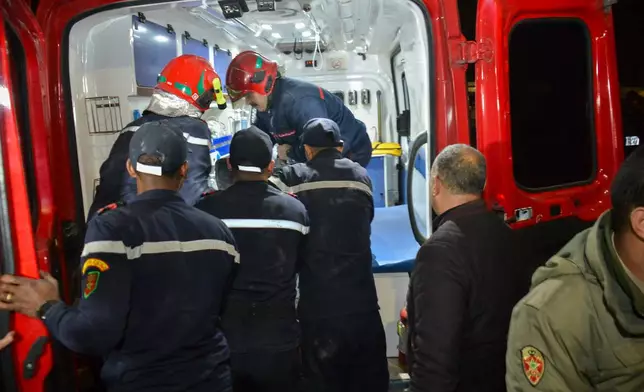 Rescue workers carry a body to an ambulance after recovering it from the wreckage of two collapsed buildings in Fez, Morocco, Tuesday, Dec. 9, 2025. (AP Photo/Ahmed Alaoui Mrani)