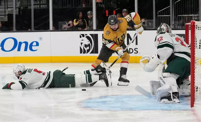 Vegas Golden Knights right wing Alexander Holtz (26) passes arouind Minnesota Wild defenseman Jake Middleton (5) during the second period of an NHL hockey game Monday, Dec. 29, 2025, in Las Vegas. (AP Photo/John Locher)