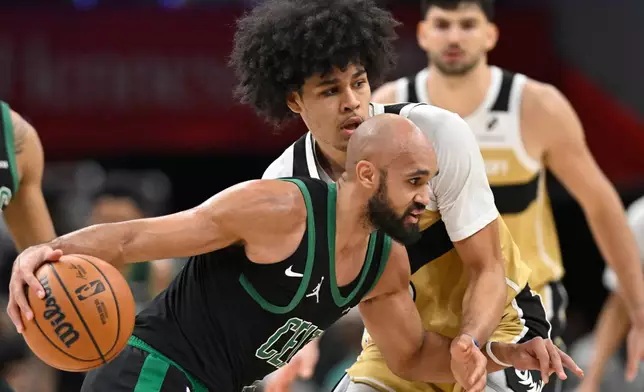 Boston Celtics guard Derrick White, front, dribbles against Washington Wizards forward Kyshawn George, top, during the first half of an NBA basketball game Thursday, Dec. 4, 2025, in Washington. (AP Photo/John McDonnell)