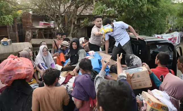 Volunteers distribute relief goods to survivors at a village affected by flash flood in Pidie Jaya, Aceh province, Indonesia, Tuesday, Dec. 2, 2025. (AP Photo/Reza Saifullah)