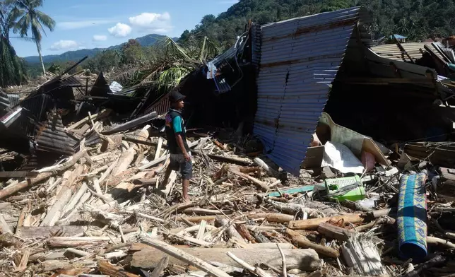 A flood survivor stands at the ruin of a house at a village affected by flash flood in Batang Toru, North Sumatra, Indonesia, Wednesday, Dec. 3, 2025. (AP Photo/Binsar Bakkara)