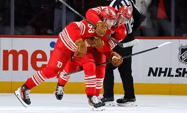 Detroit Red Wings defenseman Moritz Seider (53) is hugged by center Andrew Copp (18) after scoring during overtime to defeat the Washington Capitals in an NHL hockey game Sunday, Dec. 21, 2025, in Detroit. (AP Photo/Duane Burleson)
