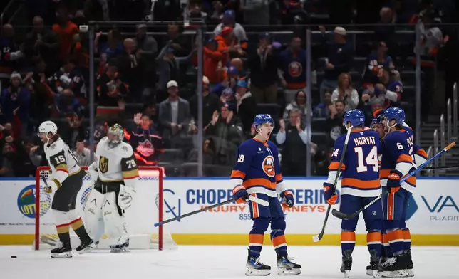 New York Islanders players celebrate a goal by Bo Horvat (14) during the first period of an NHL hockey game against the Vegas Golden Knights, Tuesday, Dec. 9, 2025, in Elmont, N.Y. (AP Photo/Heather Khalifa)