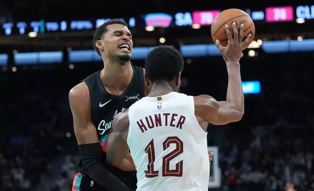 San Antonio Spurs forward Victor Wembanyama, left, crashes into Cleveland Cavaliers forward De'Andre Hunter (12) as they chase a loose ball during the second half of an NBA basketball game in San Antonio, Monday, Dec. 29, 2025. (AP Photo/Eric Gay)