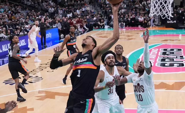 San Antonio Spurs forward Victor Wembanyama (1) is fouled as he tries to score past Cleveland Cavaliers center Jarrett Allen (31) and guard Darius Garland (10) during the second half of an NBA basketball game in San Antonio, Monday, Dec. 29, 2025. (AP Photo/Eric Gay)