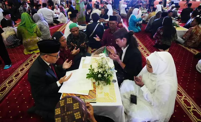 A bride and groom, right, pray after getting married during a mass wedding ceremony at Istiqlal Mosque in Jakarta, Indonesia, Wednesday, Dec. 3, 2025. (AP Photo/Tatan Syuflana)