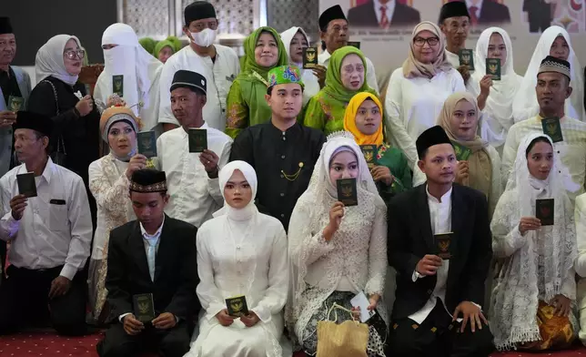 Brides and grooms pose for a group photo after a mass wedding ceremony at Istiqlal Mosque in Jakarta, Indonesia, Wednesday, Dec. 3, 2025. (AP Photo/Tatan Syuflana)