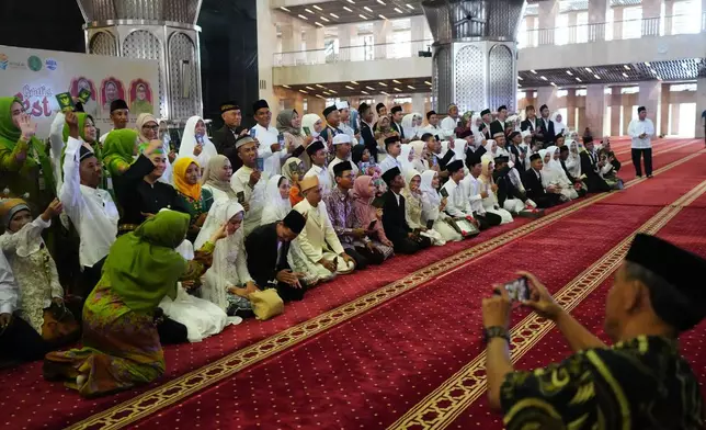 Brides and grooms prepare for a group photo after a mass wedding ceremony at Istiqlal Mosque in Jakarta, Indonesia, Wednesday, Dec. 3, 2025. (AP Photo/Tatan Syuflana)